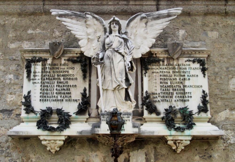 A war memorial in the form of a stone plaque with two lists of names, at the centre of which is a stone angel