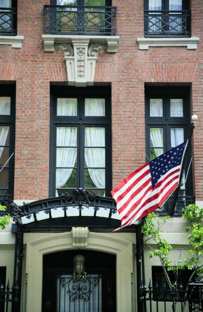 A brownstone walkup with an American flag waving in the breeze above the entrance